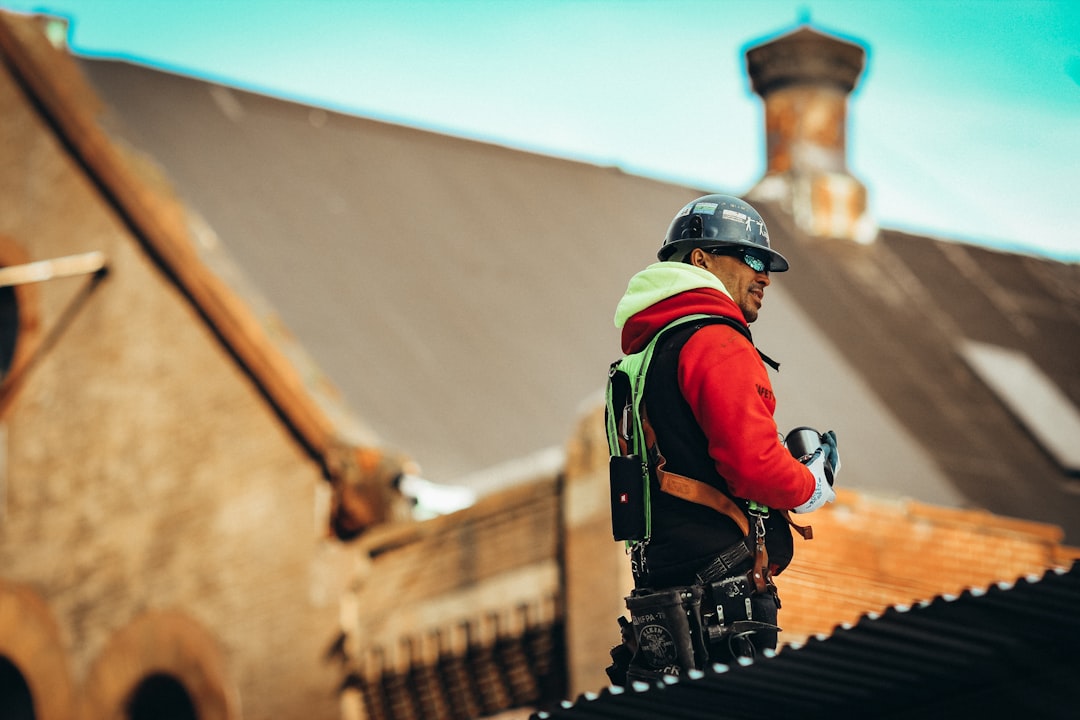A skilled and reputable roofing contractor wearing safety gear carefully installs new architectural shingles on the roof of a residential home, showcasing quality workmanship.