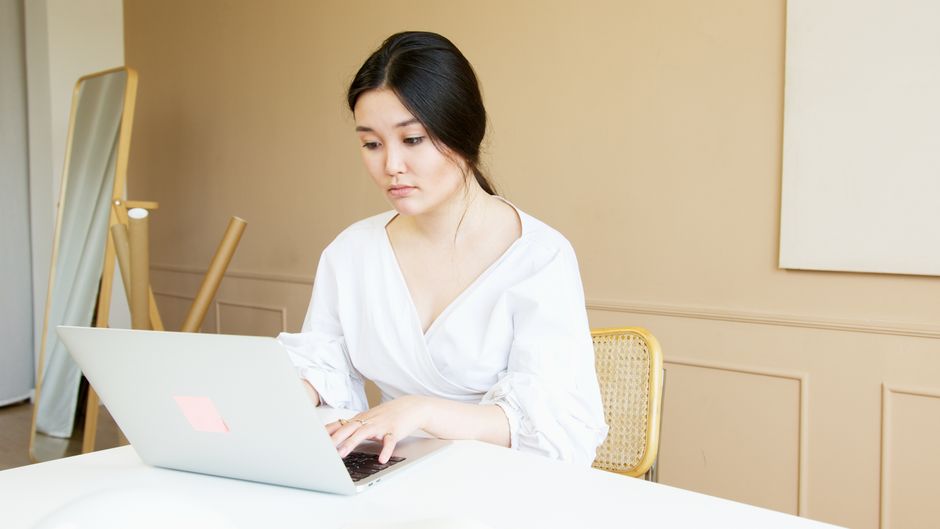 A focused woman, representing a homeschool blogger, works intently on her laptop in a bright and organized home office, illustrating the dedicated DIY SEO approach.