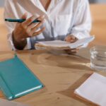 Person sits at a bright, professional desk carefully comparing notes in two different open notebooks, symbolizing the stra...